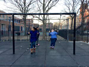Middle schoolers swinging with the chain-linked schoolyard fences in the background.